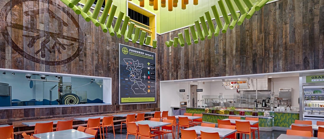 Food Shed Cafe dining room inside the Children's Discovery Museum, with orange chairs, reclaimed wood walls and a grab-and-go counter